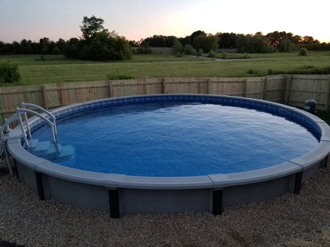 Done: the finished pool filled with water at dusk, fence and lawn behind