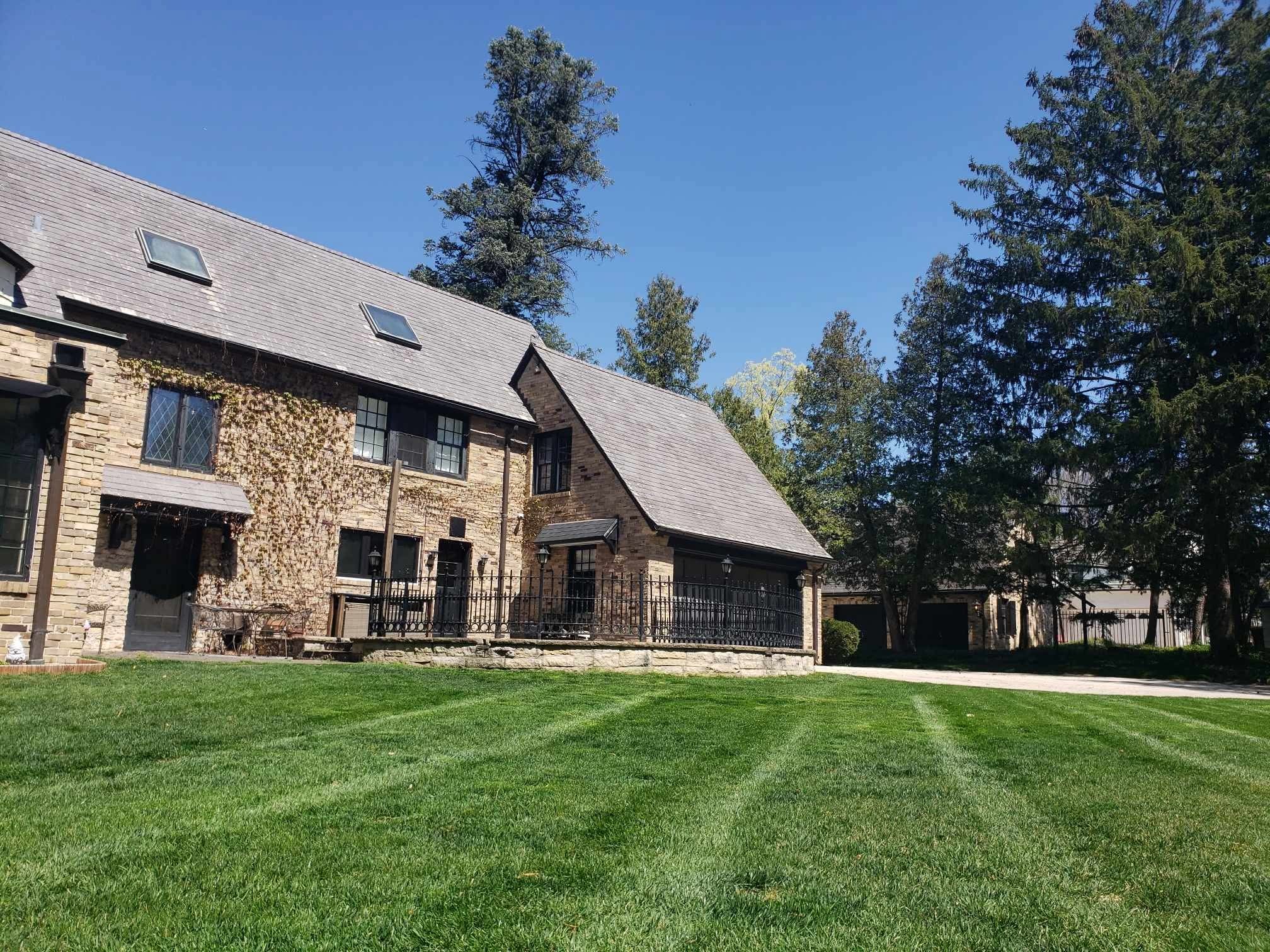 Striped front lawn in front of a stone house